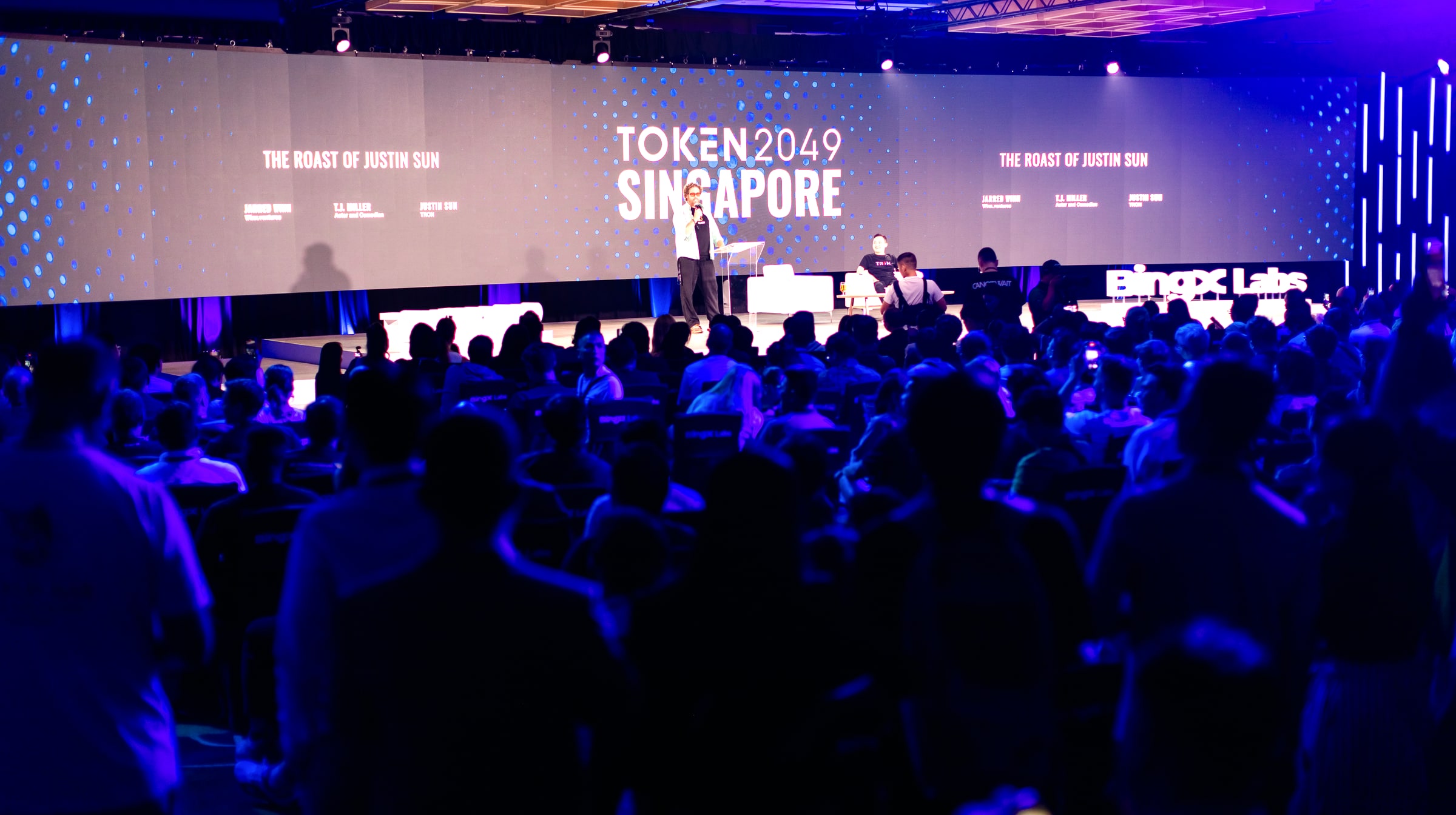 The 2025 roast — the main stage at Token2049 Singapore, TOKEN2049 screens flanking, the hall packed to the walls